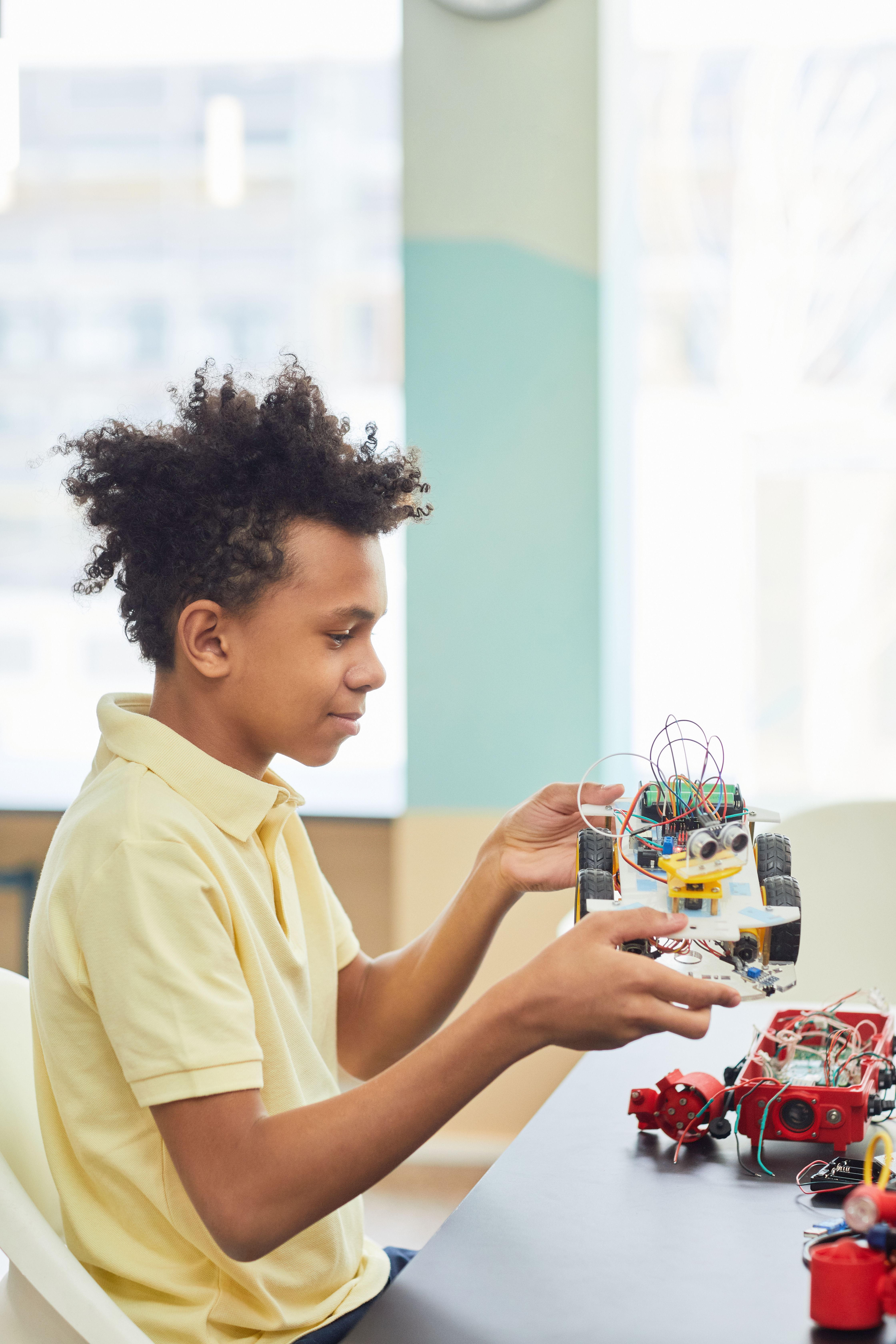 Boy building a robotics kit during a STEM enrichment session at primary school